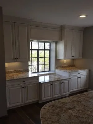 Gray kitchen cabinets with granite counters, island, and glass door to patio
