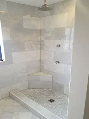 Walk-in shower with subway tile walls, marble mosaic floor, frameless glass door, and dual fixtures