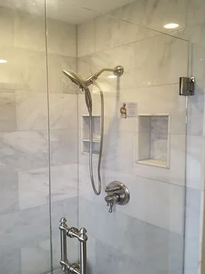 Marble tile shower with frameless glass door and polished nickel fixtures